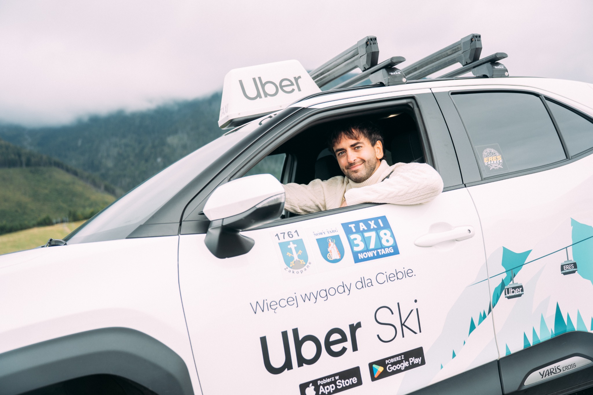 Kierowca za kierownicą Toyoty Yaris Cross z oryginalnym oznaczeniem Uber Ski
